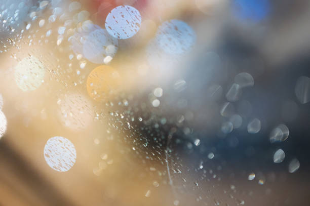 Defocused bokeh night lights and water droplets on rainy at window at night