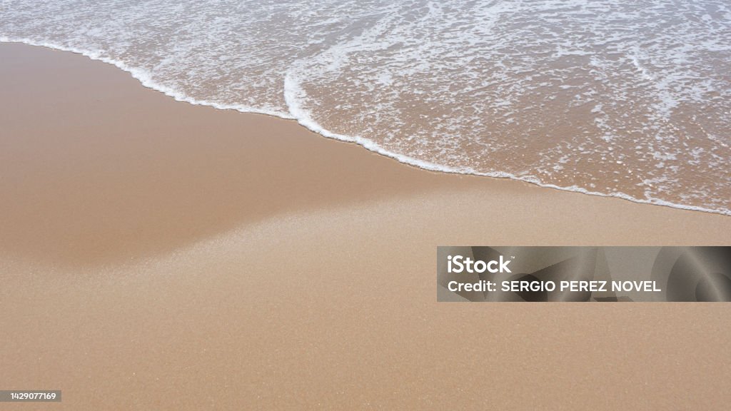 sea foam breaking on a golden sandy beach Beach Stock Photo