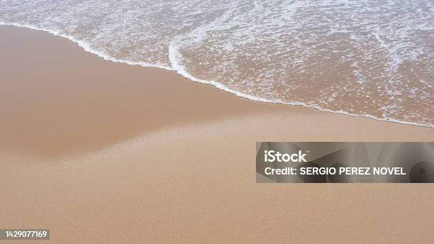 Sea Foam Breaking On A Golden Sandy Beach Stock Photo - Download Image Now - Beach, Breaking, Breaking Wave