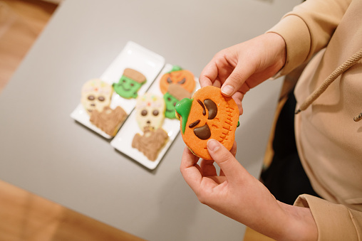 A hand taking a pumpkin Halloween themed cookie