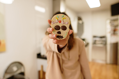 Woman holding a day of the dead (dia de los muertos) themed cookie