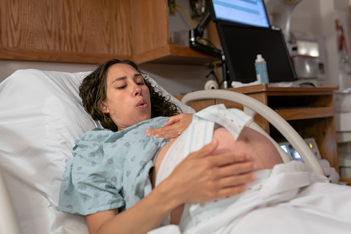 Pregnant Woman Having Contractions And Heartbeat Monitored In Hospital Bed