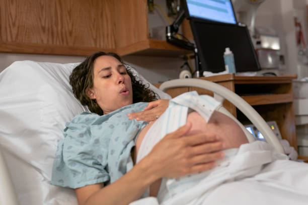 Pregnant Woman Having Contractions And Heartbeat Monitored In Hospital Bed stock photo