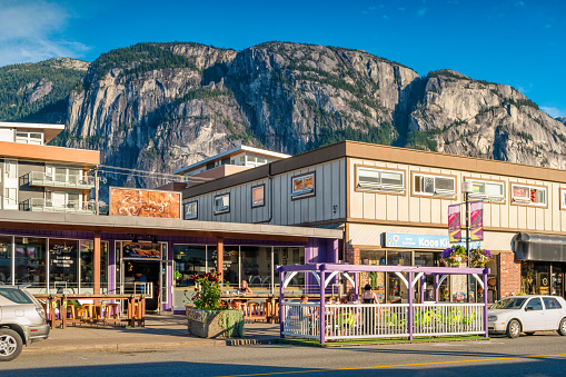 People sit on the patio of a cafe restaurant in downtown Squamish, British Columbia, Canada on a sunny day.