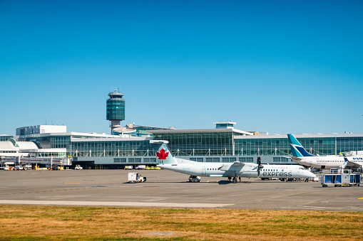 Airplanes are parked on the tarmac at Vancouver International Airport in Vancouver, BC, Canada on a sunny day.