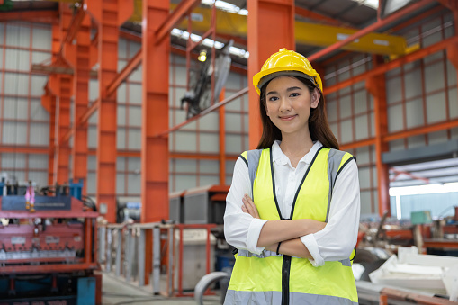 Portrait of Female Industrial Worker Standing with Arm Crossed in the Factory