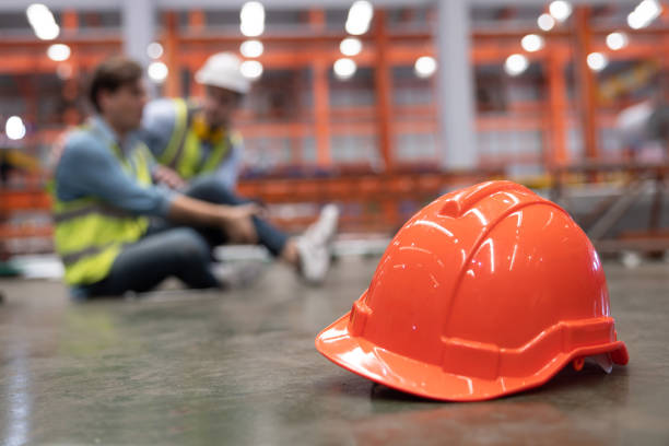 istock Red Hard Hat with Blurred Injured Factory Workers as Background 1429088763