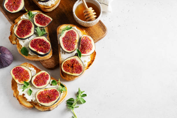 Fig bruschetta, bread and cream cheese and fruit on white background