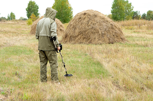 Man with electronic metal detector device working on outdoors. Close-up photography of searching antiques process.