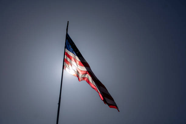太陽を背後に持つ明るい晴れた日の風に吹かれるアメリカ合衆国のアメリカ国旗 - american flag star shape striped fourth of july ストックフォトと画像