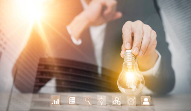 istock Businessman hand holding light bulb with icon on wood cube and   working on desk, Creativity and innovation are keys to success.Concept of new idea and innovation with Brain and light bulbs, 1429095899