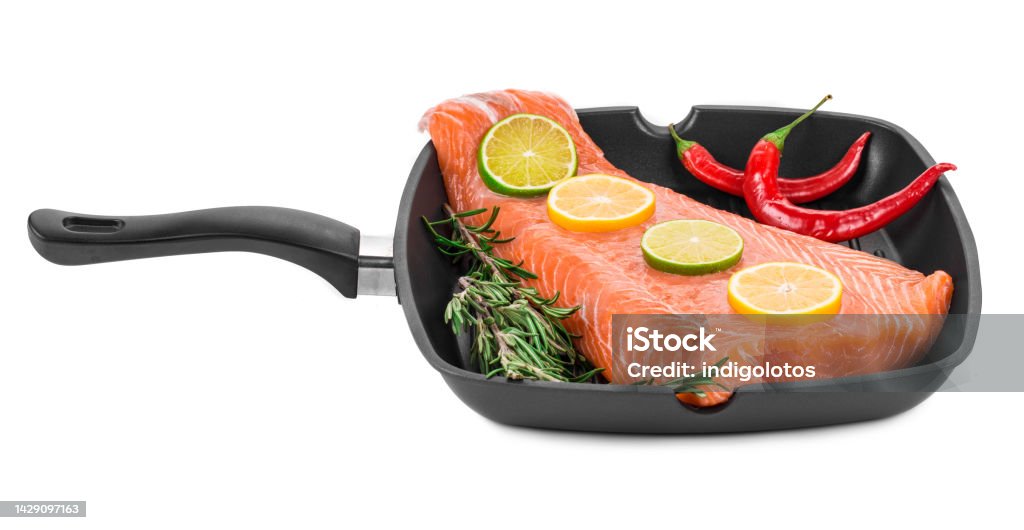 Fresh salmon fillet in a non-stick frying pan. Fresh salmon fillet in a non-stick frying pan. Isolated on a white background. Close-up. Animal Body Part Stock Photo