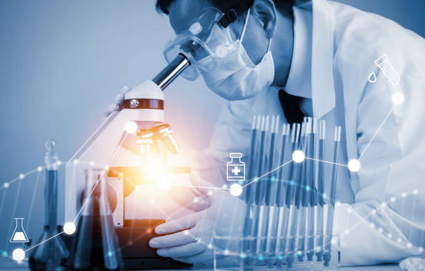 istock biochemical research scientist working with a microscope for the virus,Doctor man write a history of the experimental results in a , laboratory glassware containing chemical liquid for design. 1429098539