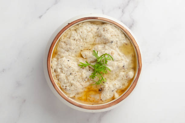 Close-up of Malai Paneer or Kali Mirch or Kalimirch, prepared in a white creamy(malai) gravy and black pepper powder sprinkled over it garnished with fresh green coriander leaves . served in a ceramic bowl over white granite background Selective focus primer plano de malai paneer o kali mirch o kalimirch, preparado en una salsa blanca cremosa (malai) y pimienta negra en polvo espolvoreada sobre ella adornada con hojas de cilantro verde fresco. servido en un cuenco de cerámica sobre fondo de granito bla
