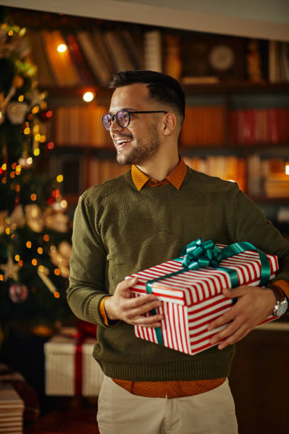 Smiling man holding Christmas gift stock photo