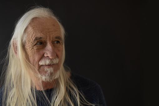 Smiling beautiful old man - rock fan -
 is posing with gray long hair. Horizontally.