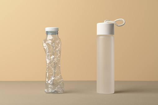 No plastic, Zero Waste, Sustainable Lifestyle. Choice Plastic Free Items alternative to disposable. Crumpled plastic bottle and glass bottle on beige background.