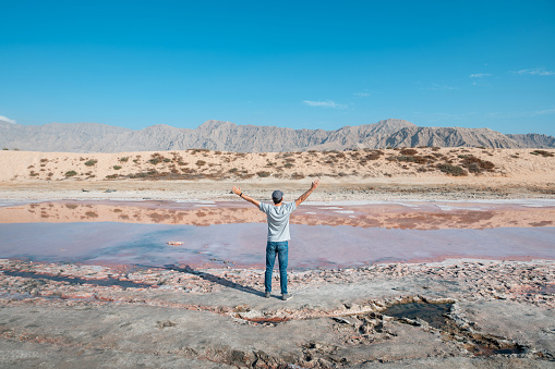 Man visiting Pink lake in Ras al Khaimah a natural phenomenon occurring in the water near seaside in the United Arab Emirates north emirate