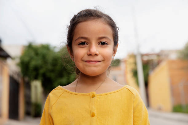 The portrait of a cute little girl who is smiling and looking at the camera in her room
