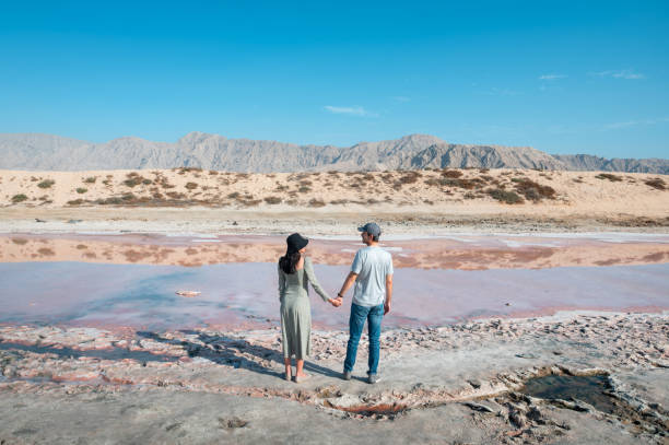 пара посещает розовое озеро в рас-эль-хайме природное явление, происходящее в воде недале�ко от моря в объединенных арабских эмиратах - ras al khaimah стоковые фото и изображения