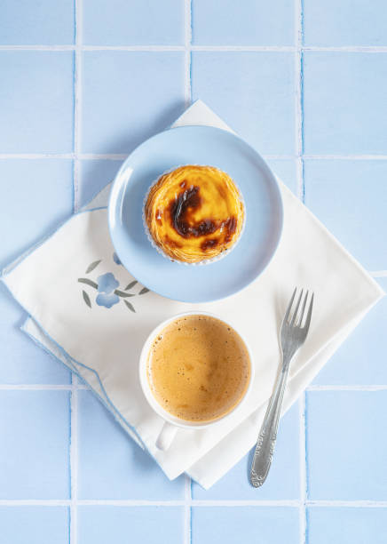 Portuguese dessert Pastel de nata with coffee on blue tile Traditional Portuguese egg tart dessert Pasteis Pastel de nata or Pastels de Belem with a cup of coffee and fork on the blue tile. Flat lay pasteis de belem stock pictures, royalty-free photos & images