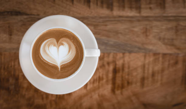 istock Cappuccino cup with latte art heart on wooden table from above. 1429122993