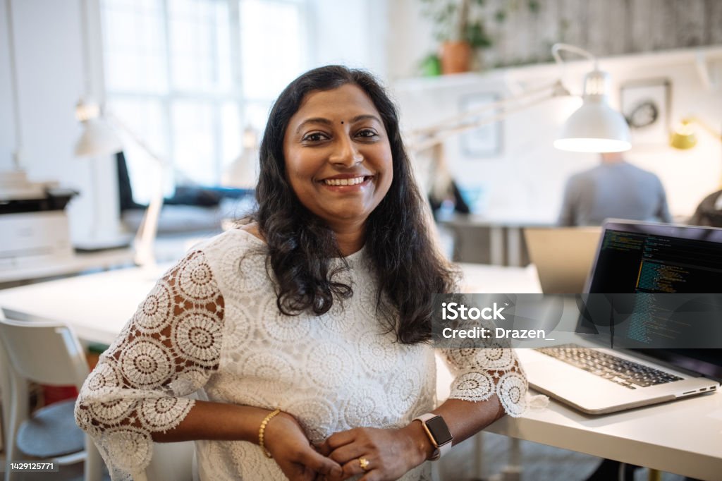 Portrait of mature Indian female employee in office. Indian businesswoman looking at camera Diverse entrepreneurs and small business owners working in coworking space.Programmers and software engineers working in office Women Stock Photo