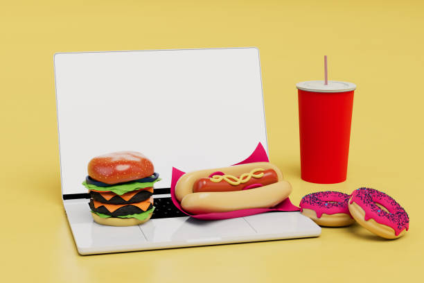 istock fast food snacks at work. laptop on which a cheeseburger, hot dog, donuts and cola. 3d render 1429127016