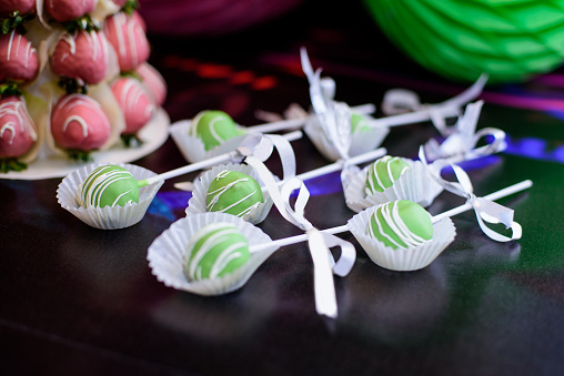 Green cake-pops with ribbons on candy bar.