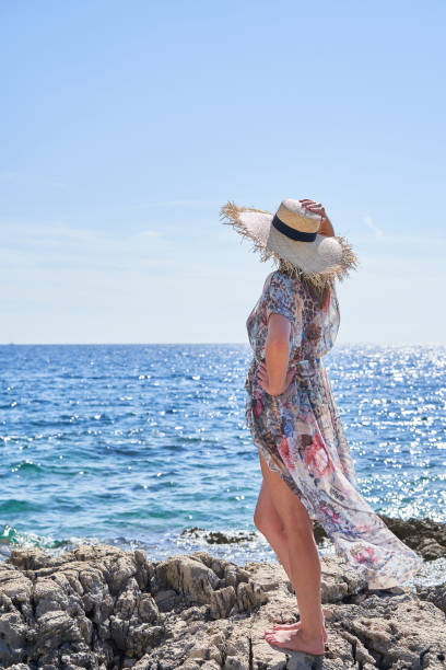 istock A woman is seen from behind. clothes fluttering in the wind. straw hat. 1429130089