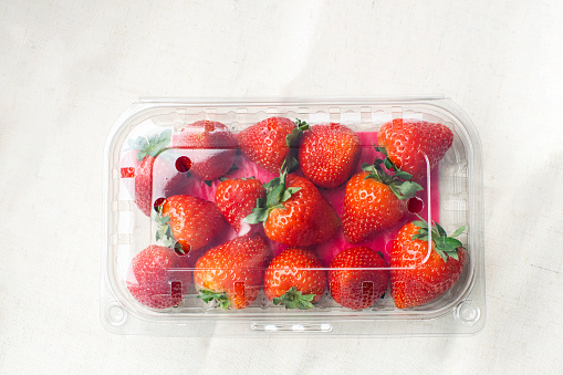 Sweet fresh strawberries in plastic container on the table. Supermarket shop plastic box container with fresh red fruits. package for strawberry.
