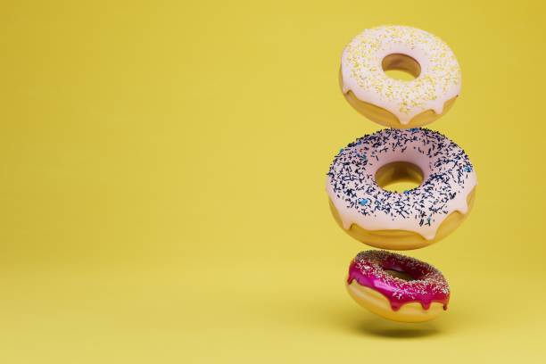 istock donuts covered with multi-colored glaze standing on top of each other on a yellow background. copy paste. 3D render 1429133441