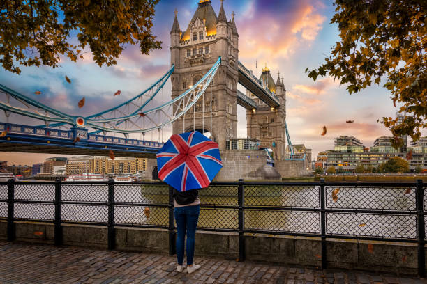 um turista segurando um guarda-chuva de bandeira britânica em frente à famosa ponte da torre - uk tree city bridge - fotografias e filmes do acervo