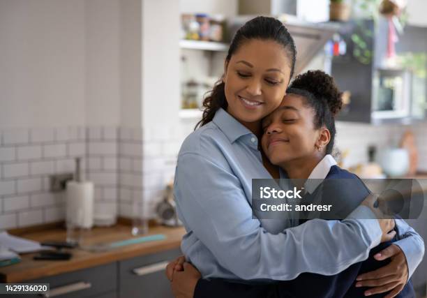Loving Mother Hugging Her Daughter After She Arrives Home From School Stock Photo - Download Image Now