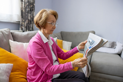 Senior woman relaxing at home reading the newspaper - active senior concepts