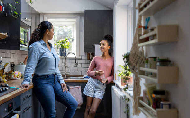 Happy mother and daughter bonding at home Happy mother and daughter bonding at home in the kitchen and talking - family concepts black mother and adult daughter stock pictures, royalty-free photos & images