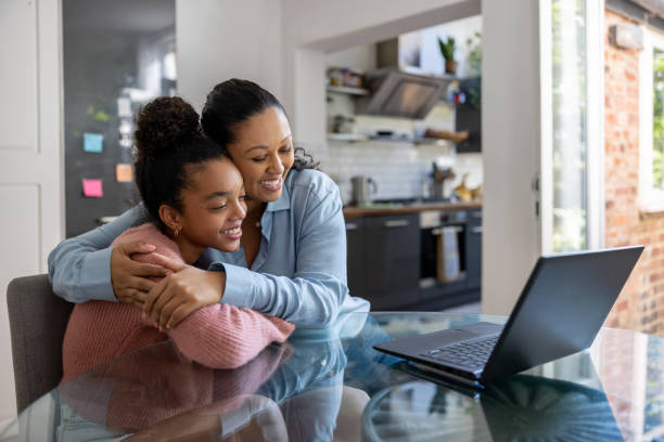 Loving mother and daughter getting good news online Loving mother and daughter getting good news online and celebrating by hugging enrollment stock pictures, royalty-free photos & images