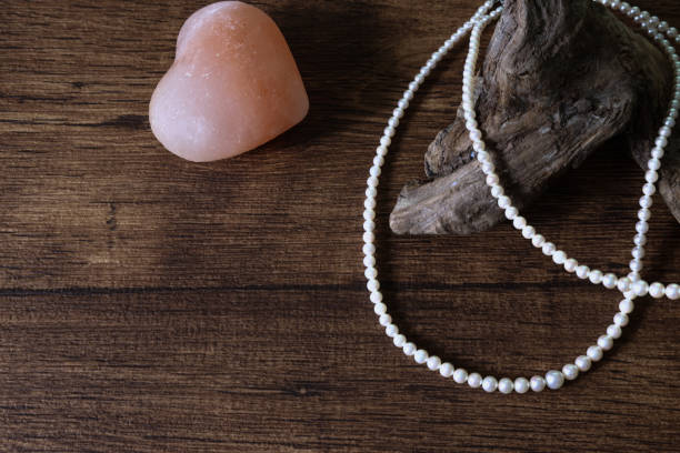 istock Pearl necklace and heart shaped object on the wooden table. 1429140405