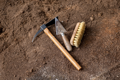 Pickaxe, trowel and brush. Tools in an archaeological excavation