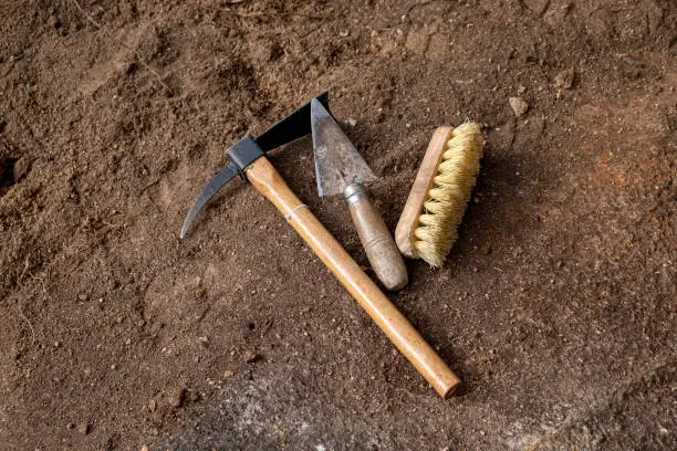 Photo of Pickaxe, trowel and brush. Tools in an archaeological excavation, digging concept
