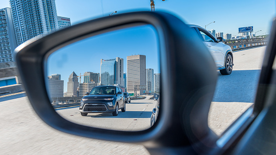 Miami, Florida, USA - September 30, 2022: Rush hour on Miami freeways is seen from the point of view of a car's side mirror.