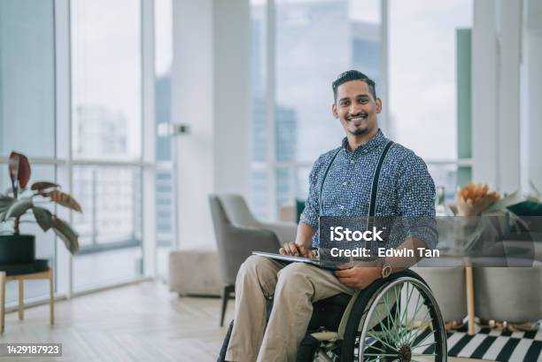 Portrait Asian Indian Male Designer With Disability In Wheelchair Looking At Camera In Business Lounge Stock Photo - Download Image Now