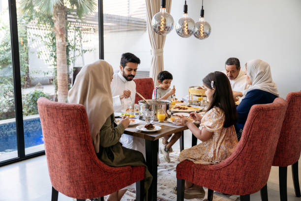 famiglia mediorientale seduta al tavolo da pranzo in casa moderna - saudi arabia child ramadan offspring foto e immagini stock