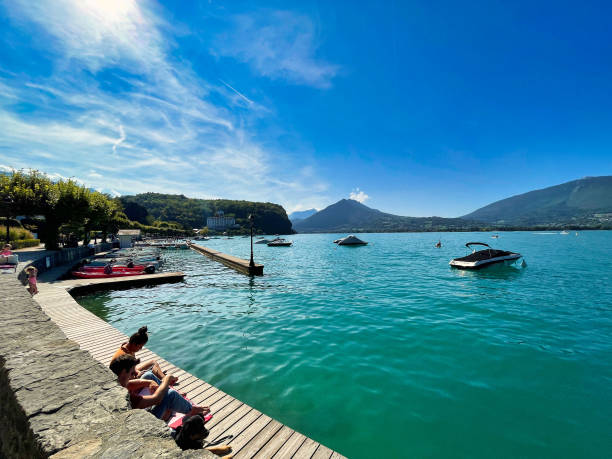 Menthon saint Bernard, France - September 12 2021 : people on a wooden dock on the lake of annecy are sun bathing in the summer