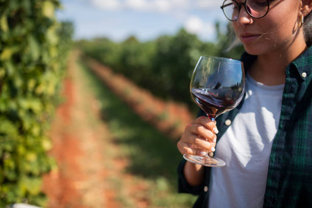 istock A beautiful woman who is a wine lover drinks wine while standing in a vineyard 1429193381