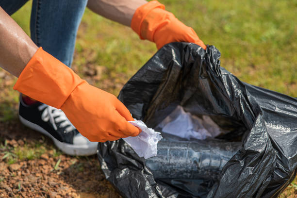 istock A man wearing orange gloves collecting garbage in a black bag. 1429224088