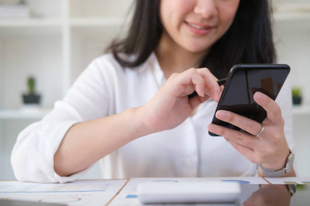 istock Smiling female employee sitting in bright office and using smart phone for communicating on social network. 1429224418