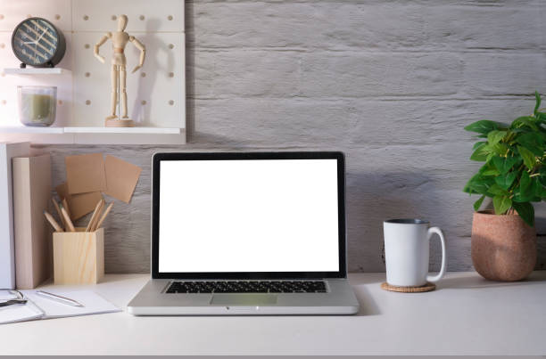 istock Bright modern home office with laptop, supplies and flower pot on white table. Empty screen for your advertise text. 1429225004