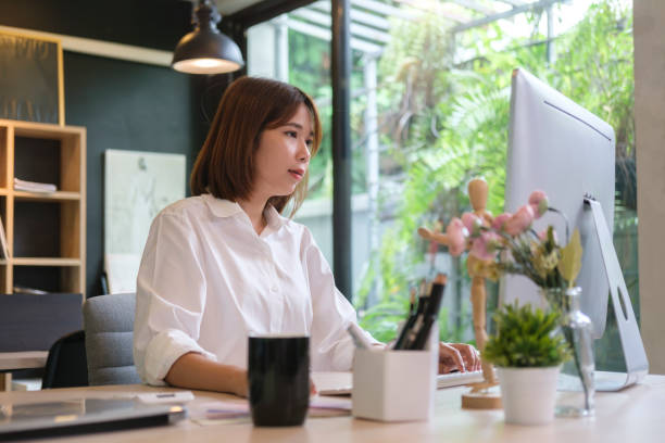 istock Concentrated asian female office worker working with computer at modern workplace. 1429225077