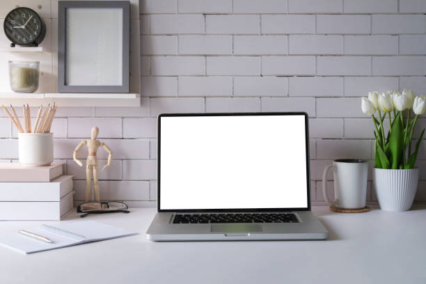 istock Laptop with empty screen, picture frame, flower pot and supplies on white table. 1429227490